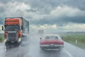semi trucks passing classic car on road during thunderstorm Queener Law