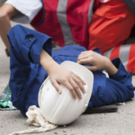 woman lying down holding hard hat after accident Queener Law