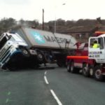 semi truck turned over with tow truck helping Queener Law