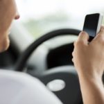 distracted male driver looking at phone not the road Queener Law