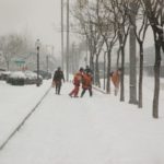 maintenance workers blowing snow off sidewalk while pedestrian walks by Queener Law