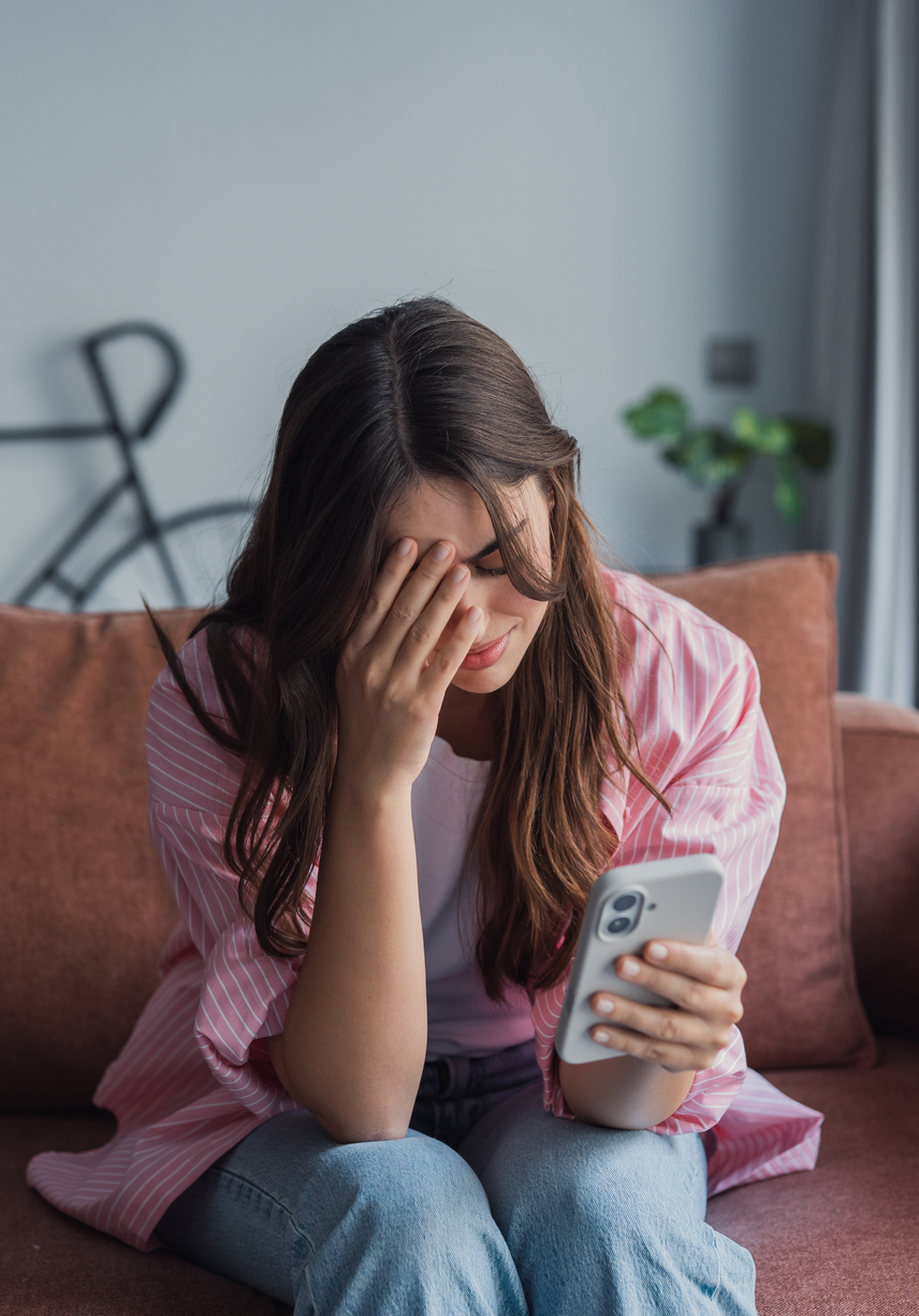 A woman looking at her smartphone, representing the emotional distress and privacy concerns that can arise when private images or videos are shared online without consent.
